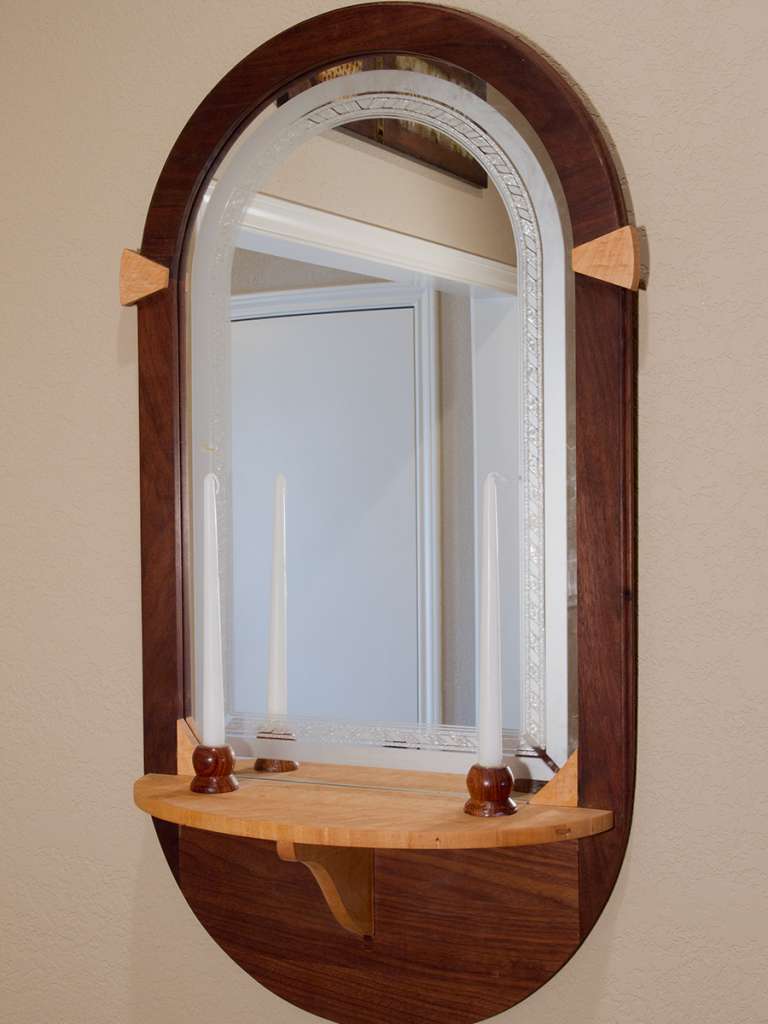 Mirror surrounded by wooden frame with small shelf underneath